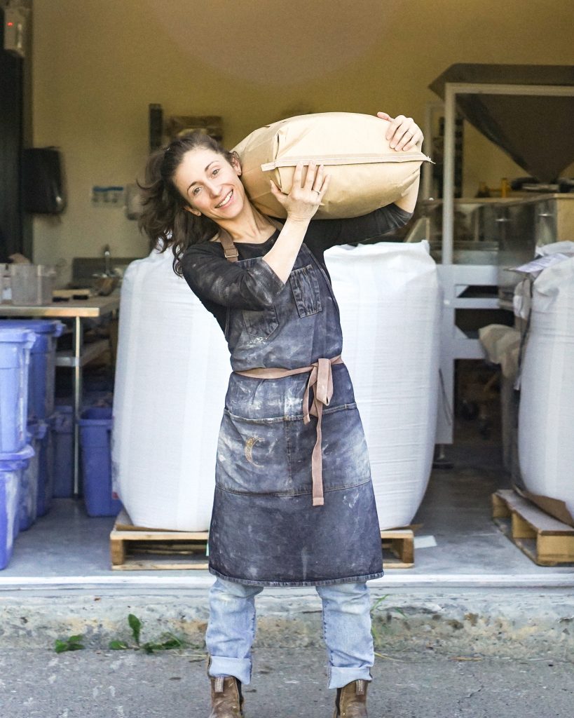 Gabrielle Prud'homme of Almanac Grain lifting a bag of grain.